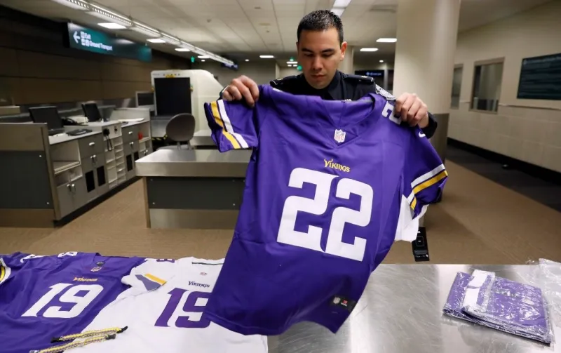 An officer with the U.S. Customs and Border Protection, Office of Field Operations, lays out a set of recently confiscated counterfeit Minnesota Vikings jerseys at a CBP facility in Minneapolis, Minn., Jan. 31, 2018. (U.S. Customs and Border Protection photo by Glenn Fawcett)