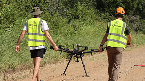 Two engineers walking a drone to a test site