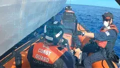 United States Coast Guard members in a boat on the water in gear.