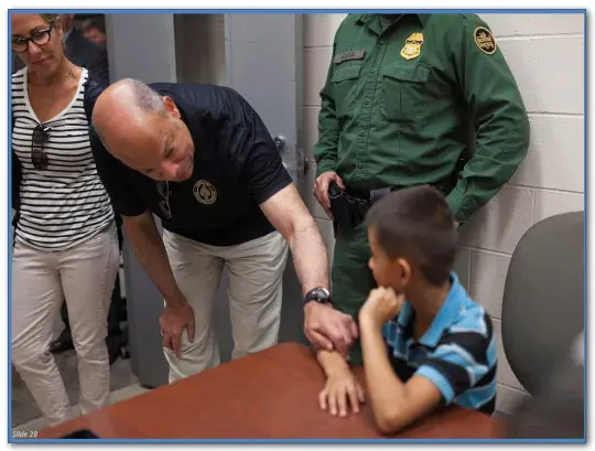 Secretary Johnson speaks with a boy being held by Customs and Border Protection