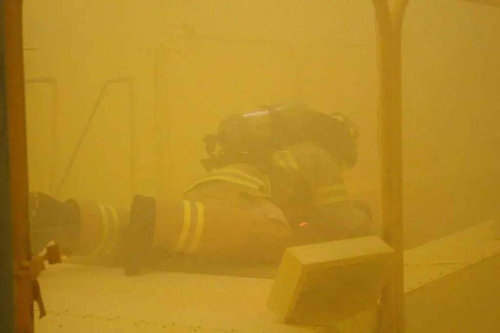 Test subject crawls on the floor of smoke-filled testing chamber
