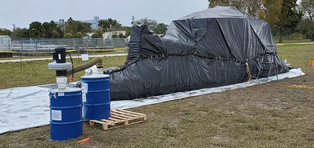 Participants wrapped the boat in plastic during the decontamination process. On the left are the barrels with activated carbon where methyl bromide is captured after the decontamination step.