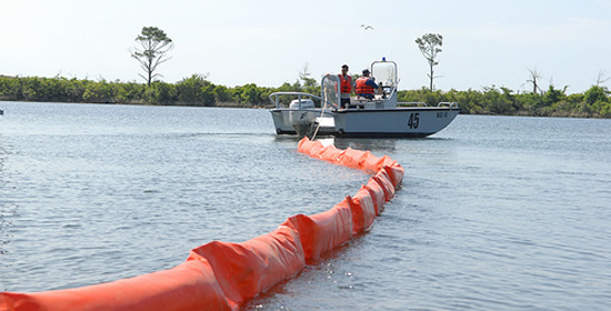 NAVAL AIR STATION PENSACOLA, Fla. - Naval Air Station Pensacola Pollution Response unit deploys an oil containment boom at Sherman Cove to protect environmentally sensitive grass beds from the Deepwater Horizon oil spill, May 4, 2010. U.S. Navy photo by Patrick Nichols.
