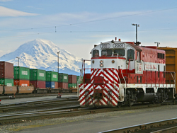 Freight train traveling through snowy mountains.