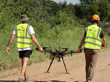 Two technicians carrying a drone prepare to deploy a target drone during the Oklahoma field demonstration.