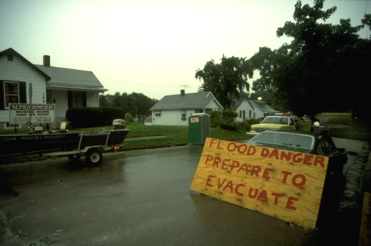 Image: A sign reads "Flood danger, Prepare to evacuate" as residents prepare for the flood