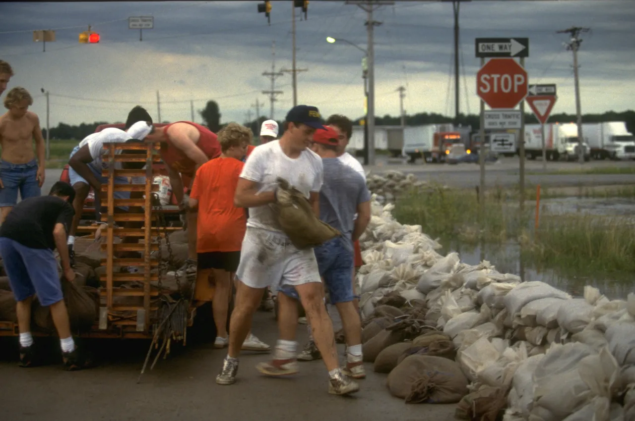 Image: Residents and volunteers work to fill sandbags in an effort to stop the flood from causing further damage