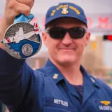 Image: Coast Guard Marathon Medal held up by an Officer