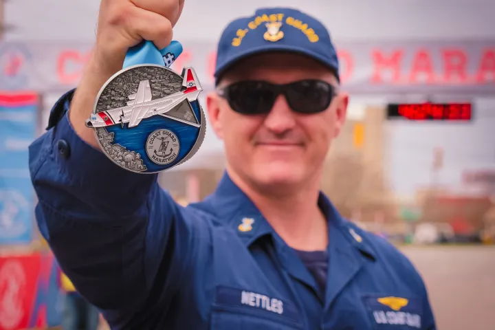 Image: Coast Guard Marathon Medal held up by an Officer