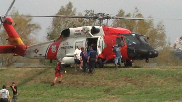 A Coast Guard helicopter on a river levee prepares to leave with survivors rescued from the flooding in Pointe Celeste.