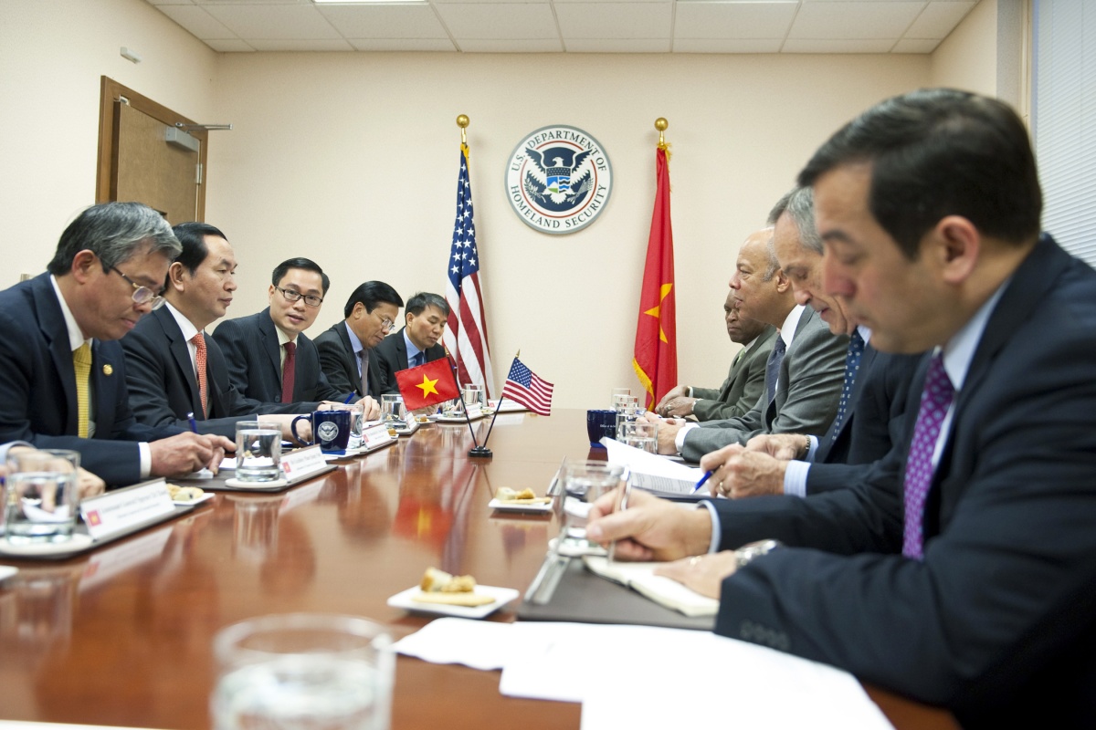 Secretary Johnson, Minister Tran Dai Quang, and associates, sit at a table to discuss strategies.