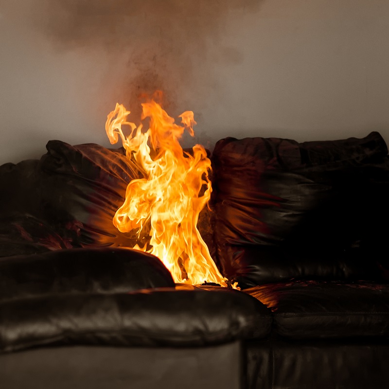 Flames rising from a burning sofa.  