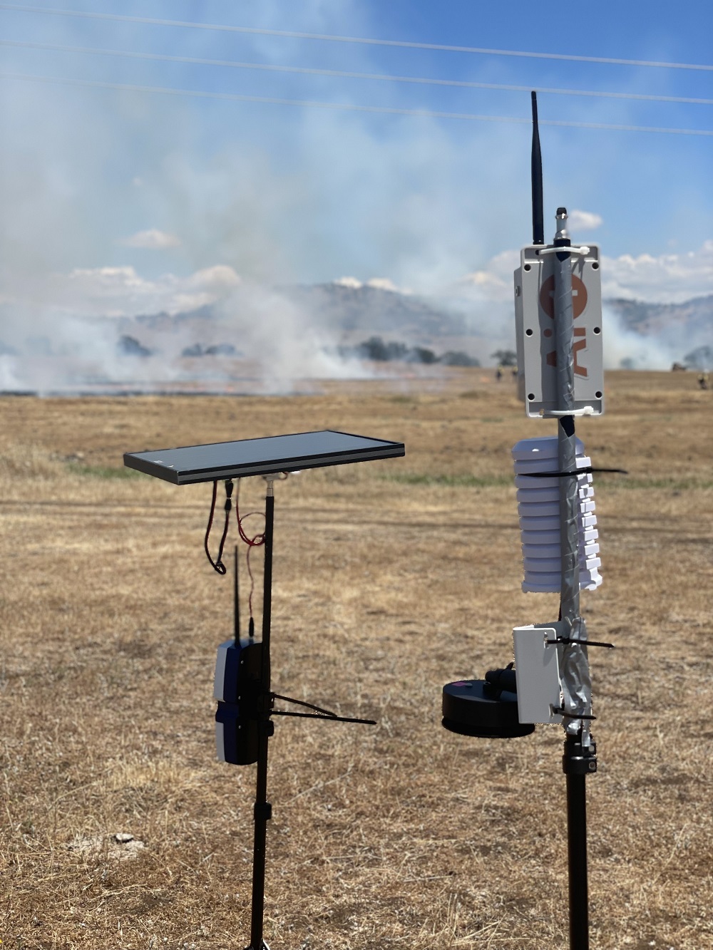 Two prototype fire sensors are shown in the foreground during a June 2021 field test in California.
