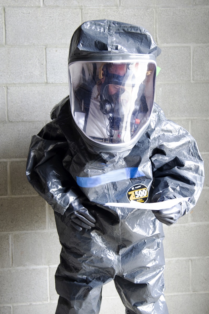 A first responder wearing personal protective equipment evaluates in-suit communications gear. 