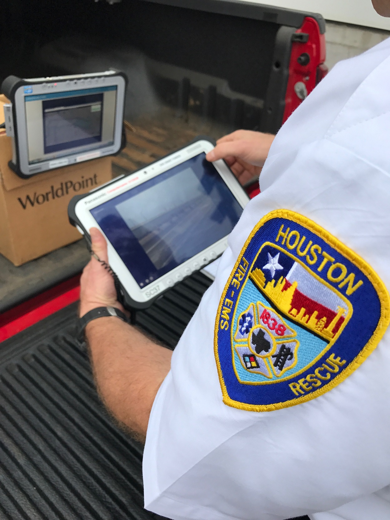 Fire-EMS responder looking at tablet with picture of highway on the screen. Fire-EMS responder's shoulder patch reads: "Houston"; "Fire-EMS"; "Rescue."