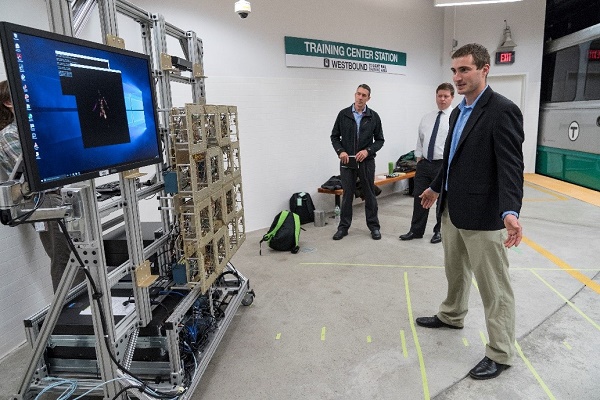 Dr. William Moulder of MIT Lincoln Laboratory standing in front of the millimeter wave imager watches his scanned image together with S&T Program Manager Don Roberts (left) and MBTA Emergency Manager Robert Creedon (center).