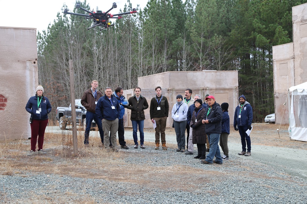 A drone test: A group of people gathered in an urban environment watch a drone as it performs specific skills.