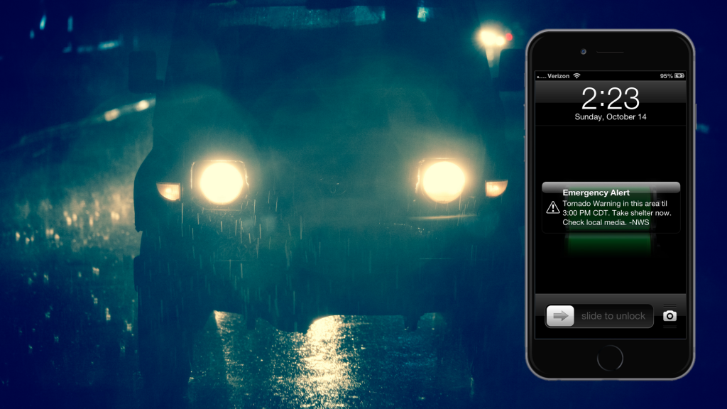 Picture of a car, driving in the rain, accompanied by the pic of a smartphone displaying the time of 2:23 on Sunday, Oct 14 and an emergency WEA alert reading: Tornado warnind in th area till 3: PM CDT. take shelter now. Check local media -- NWS