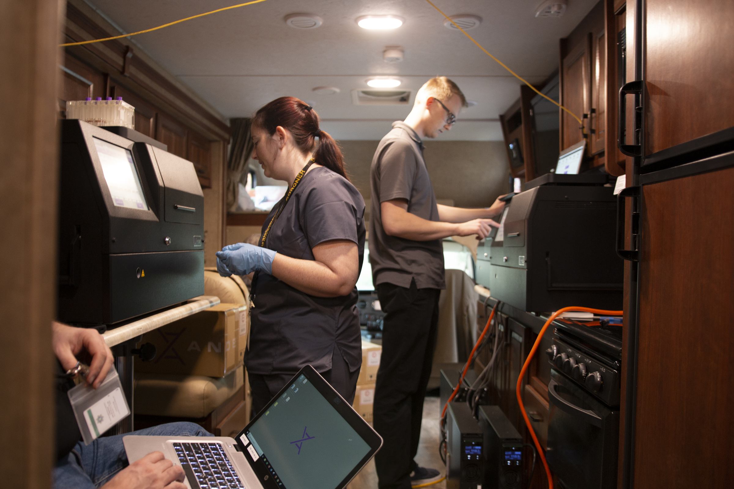 ANDE staff analyze DNA samples in their own RV equipped with three Rapid DNA machines. The RV was parked in the Coroner’s parking lot for quicker access to victim’s DNA. Image by ANDE Corporation.