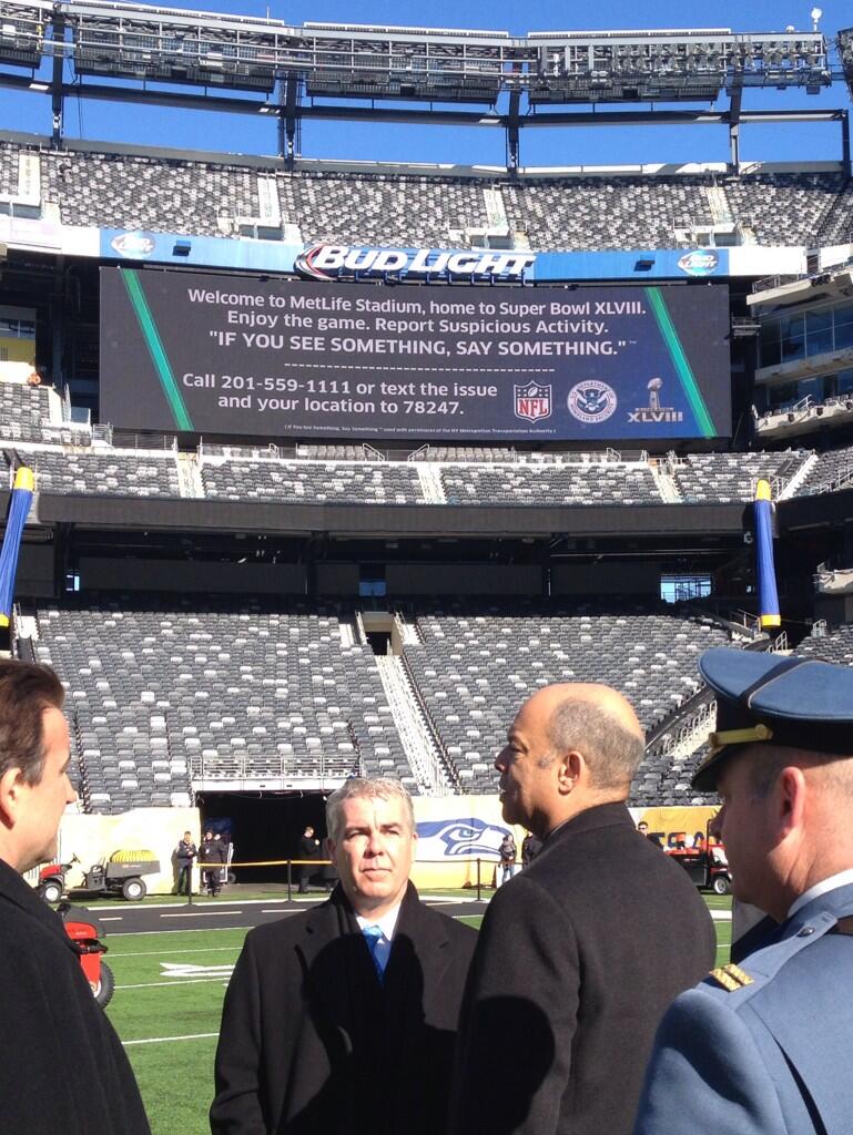 Secretary Johnson meets with security officials (including Federal Coordinator Andrew McLees, center) at MetLife Stadium during a security briefing for Super Bowl XLVIII as DHS's "If You See Something, Say Something(TM)" messaging appears on the video boards.