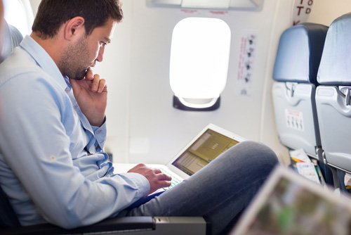 Image of a man on a plane with a laptop