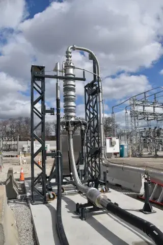 Image depicts REG system installed into the electric grid. There are black and gray pipes leading away from the gray tube shaped structure. 