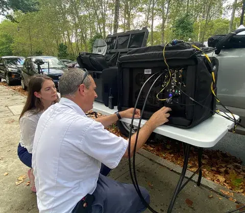 Two people examine the TDCOMM LTE network data collecting equipment,
