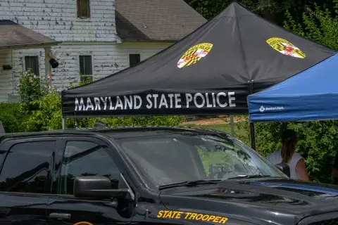 Black SUV labeled “State Trooper” parked in front of a tent labeled “Maryland State Police”.