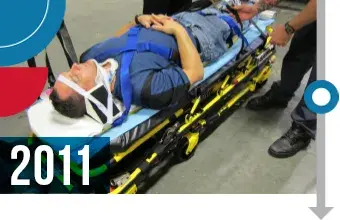 A person on a stretcher bed being attended to. 2011.