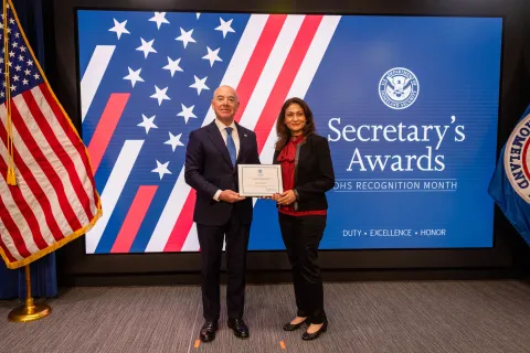 DHS Secretary Alejandro Mayorkas with Team Excellence Award recipient,  Iram Shahzad.