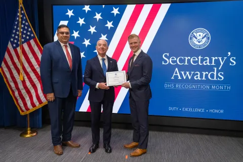 Left to Right: CISA Deputy Director Nitin Natarajan, DHS Secretary Alejandro Mayorkas, and  Innovation Award recipient, Seth McKinnis.