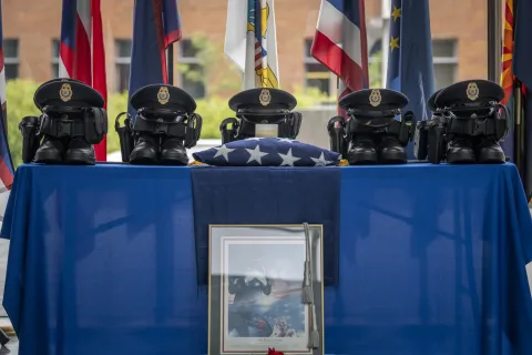 Homeland Security Secretary Alejandro Mayorkas and Deputy Secretary John Tien attend a wreath laying ceremony for fallen FPS officers during 2022 Police Week, where a set of boots, belt, and FPS uniformed hat are placed on a table with the American flag representing the fallen officers.