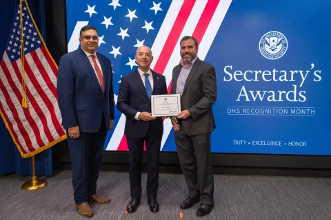 Left to Right: CISA Deputy Director Nitin Natarajan, DHS Secretary Alejandro Mayorkas, and Team Excellence Award recipient, Joshua Stankus.