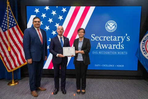 Left to Right: CISA Deputy Director Nitin Natarajan, DHS Secretary Alejandro Mayorkas, and Team Excellence Award recipient, Victoria Wallace.