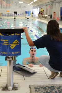 Petty Officer 1st Class Robert Troha talks to Gianna Davis, a U.S. Masters Swimming coach, during training at George Block Aquatics in San Antonio. (Photo by Petty Officer 2nd Class Grant DeVuyst)