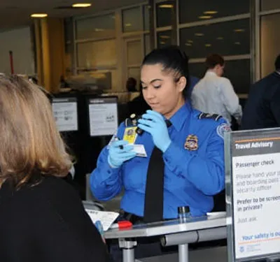 TSA agent inspecting ID before passengers enters checkpoint.