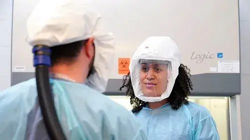 An NBACC safety officer confers with an NBACC scientist prior to an experiment being conducted in a Biosafety Level 3 lab. Powered air purifying respirators are used to protect the workers from potential aerosol exposures.