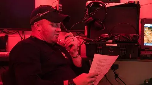Man reads a script into a radio microphone.