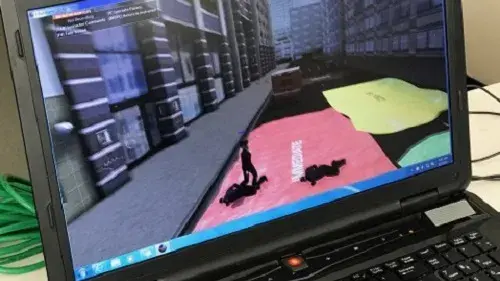 Close up shot of a laptop running an EDGE virtual training scenario. The screen depicts the medical triage area on the street outside of the hotel.