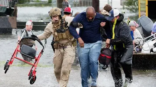 Two people helping a man out of an immediate disaster area