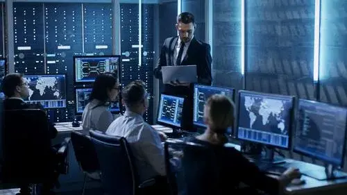Group of people looking at data on computer monitors
