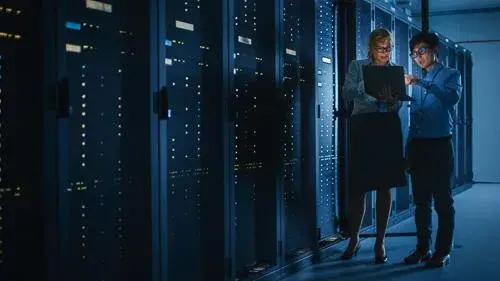 Two people standing in dark server room