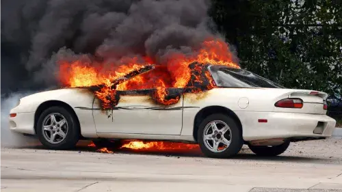 Car on fire with smoking rising from the burning vehicle 