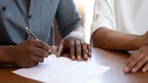 Image of a person holding a pen and signing a paper