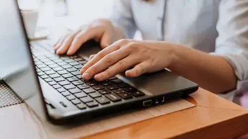 Image of fingers typing on a laptop