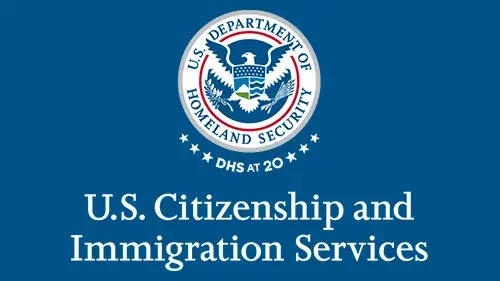 Vertical USCIS wordmark/lockup in white with "DHS at 20" below the DHS seal
