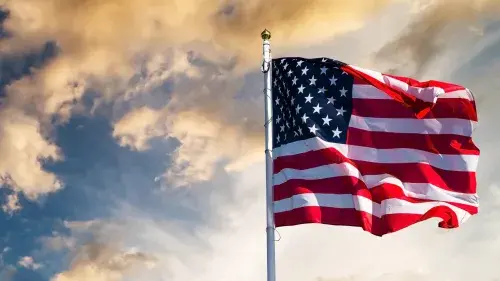 American Flag with clouds in the background.