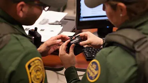 CBP Officers Look Closely at Part of a Video Incident Recording System