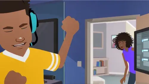 Carter in a video game headset pumps their first in excitement at winning a video game on the computer while their guardian looks in from the outside
