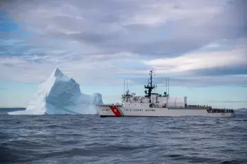 U.S. Coast Guard vessel cruises safely past an iceberg.